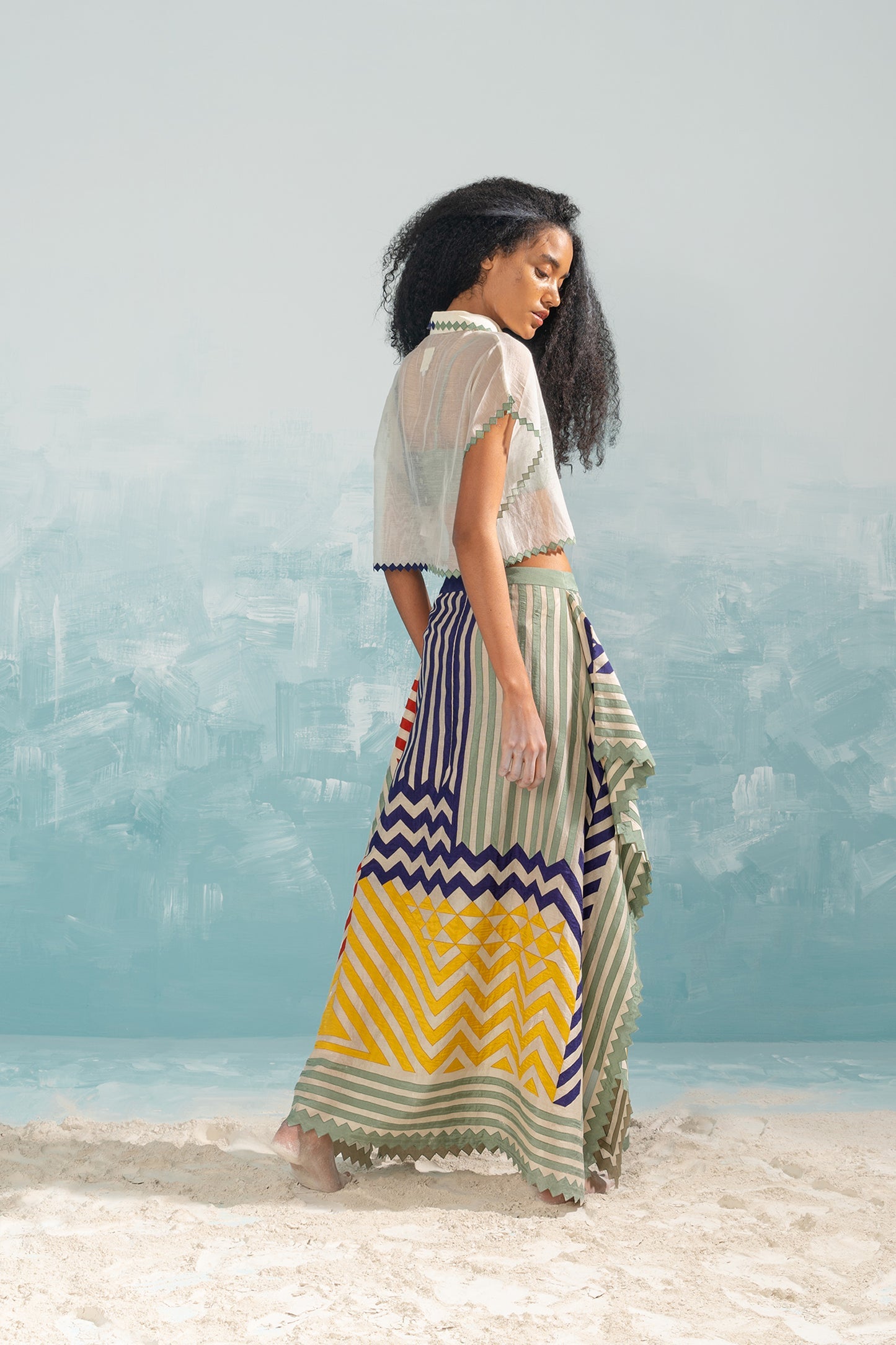 Woman wearing a colorful skirt with a white top against a light blue background