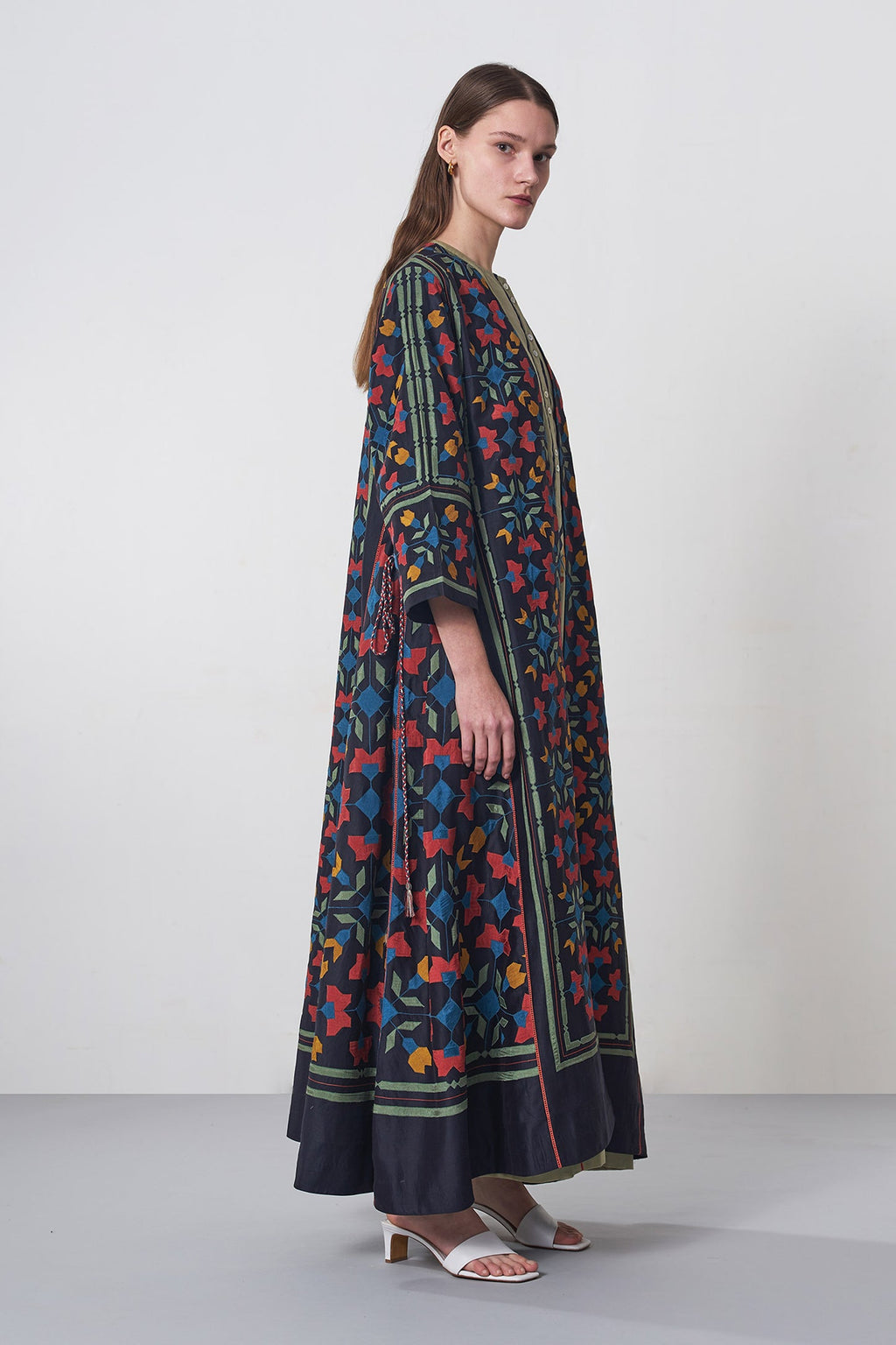 Woman wearing a long, patterned dress against a plain background