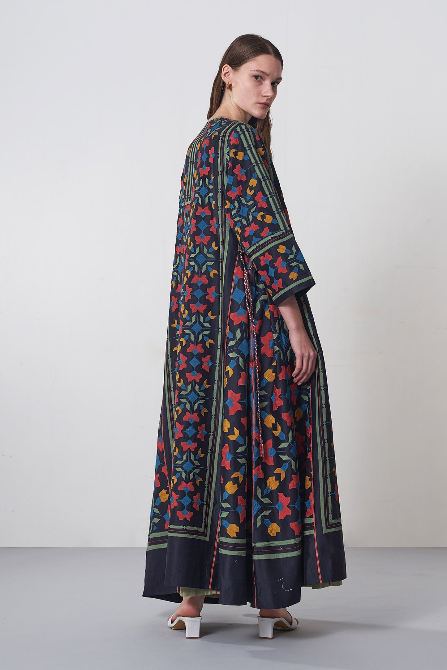 Woman wearing a long, patterned dress against a white background