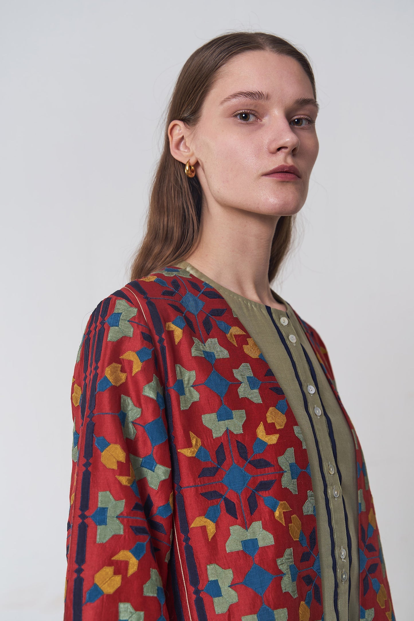 Woman wearing a colorful patterned jacket against a white background