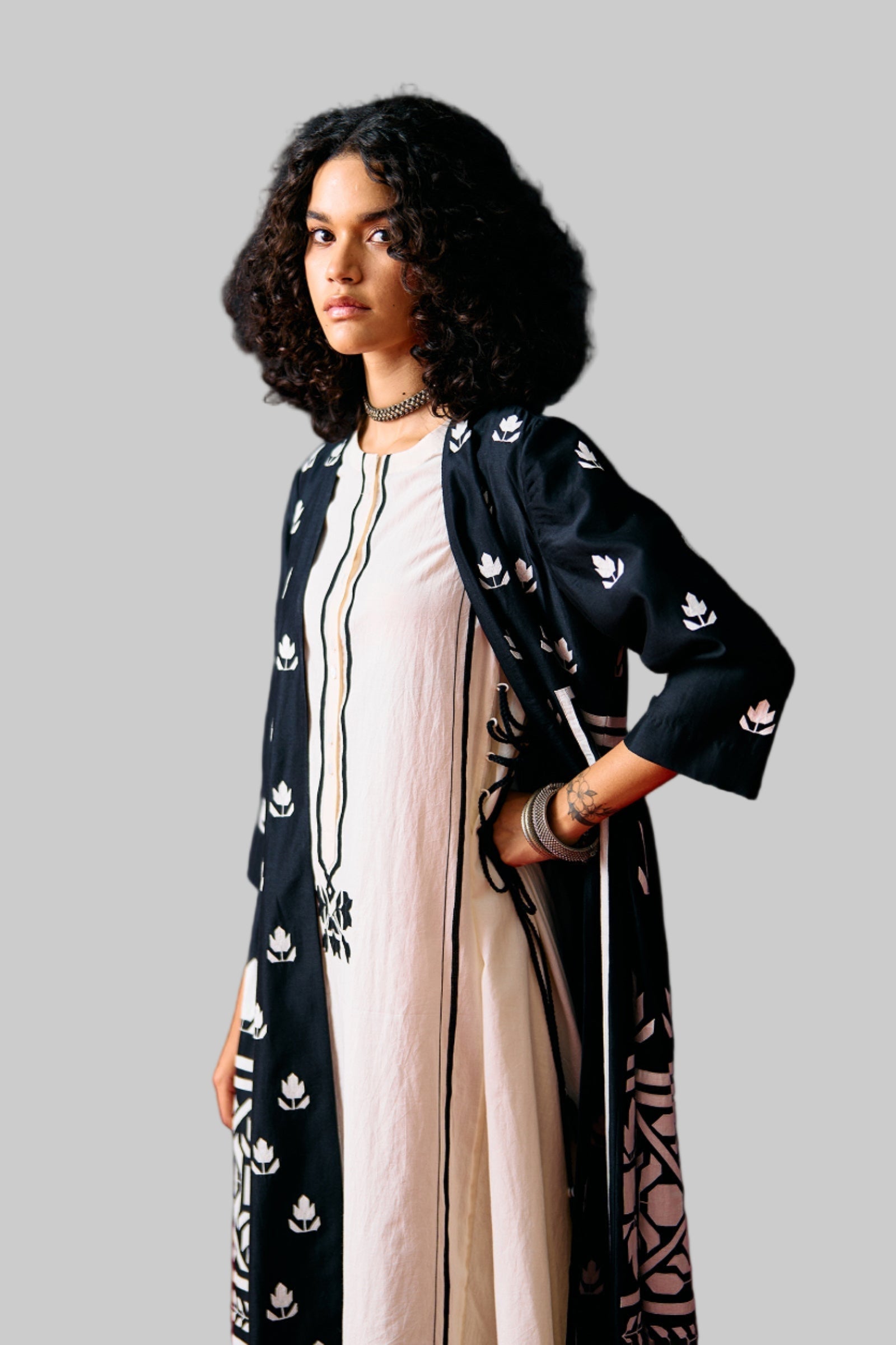 Woman wearing a black patterned outfit with a white top against a black background