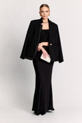 Woman wearing a black outfit with a jacket and clutch on a white background