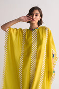 A model wearing a vibrant yellow free-size kaftan with intricate white geometric cutwork and appliqué patterns along the borders and central panels.