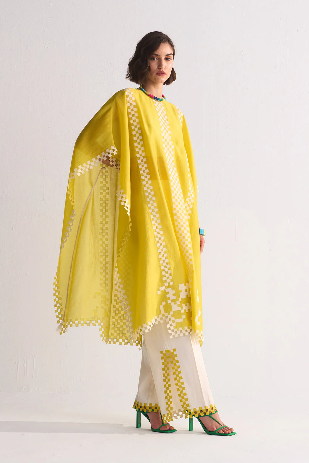 Woman wearing a yellow and white traditional outfit with a matching dupatta on a plain background
