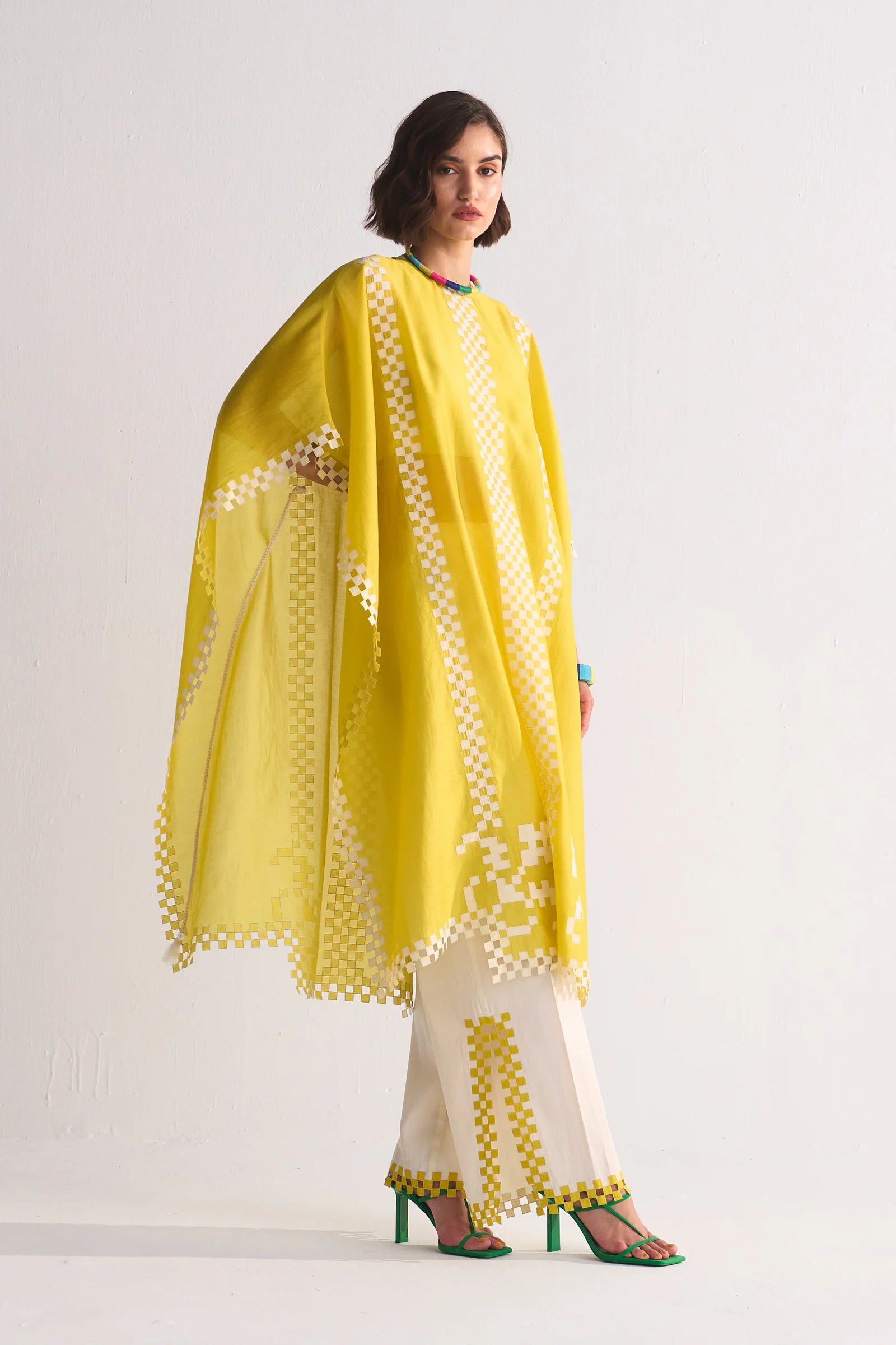 Woman wearing a yellow and white traditional outfit with a matching dupatta on a plain background