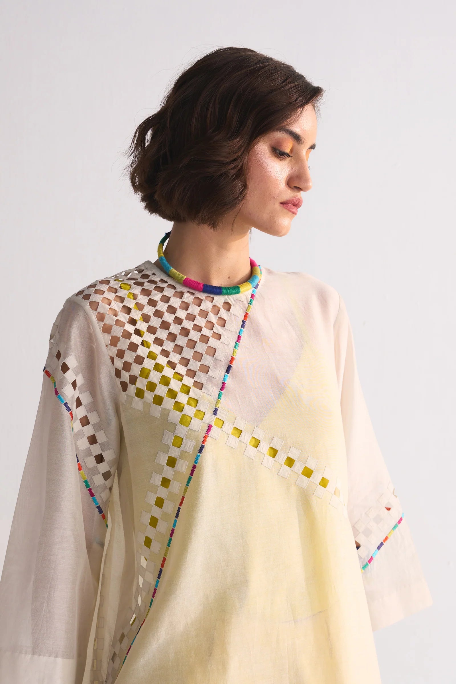 An ivory Cotton Silk Chanderi kameez featuring geometric cutwork on the shoulder and back, accented with multi-colored thread work and tonal appliqué.