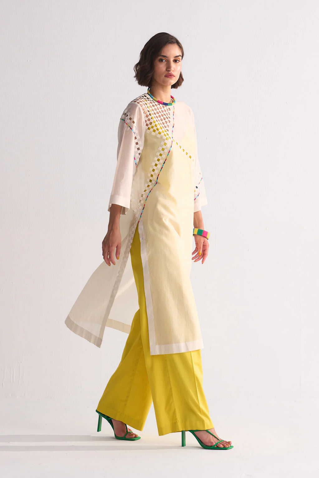 Woman wearing a traditional outfit with a yellow saree and white blouse on a white background