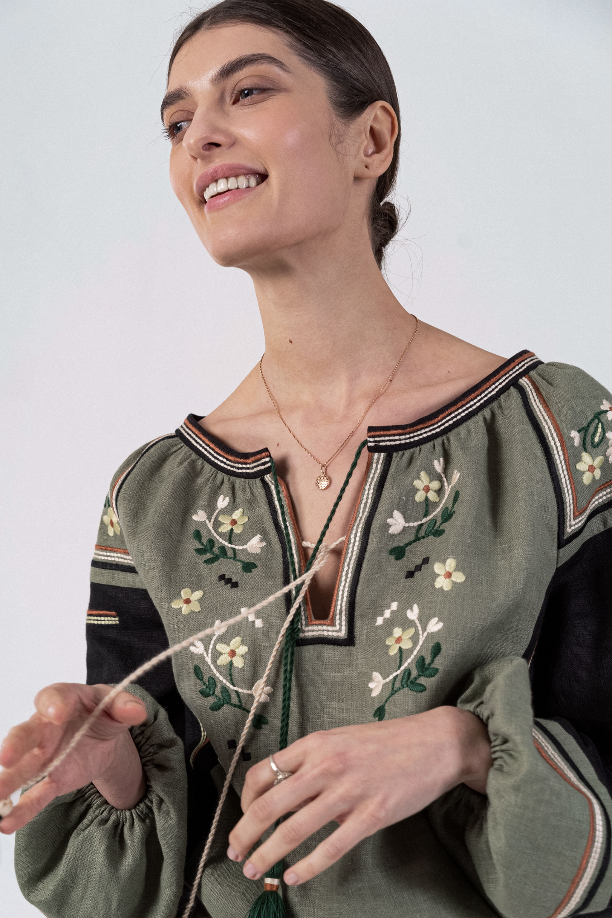 Woman wearing a green embroidered blouse with a plain background
