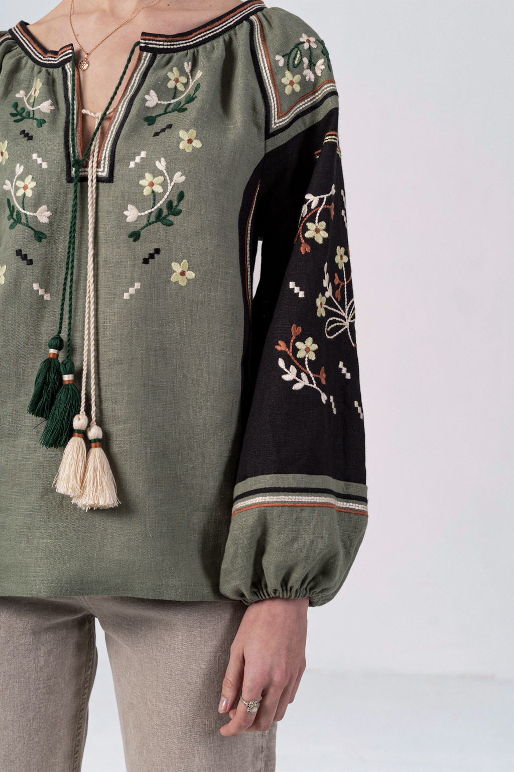 Green blouse with floral embroidery and tassels on a white background