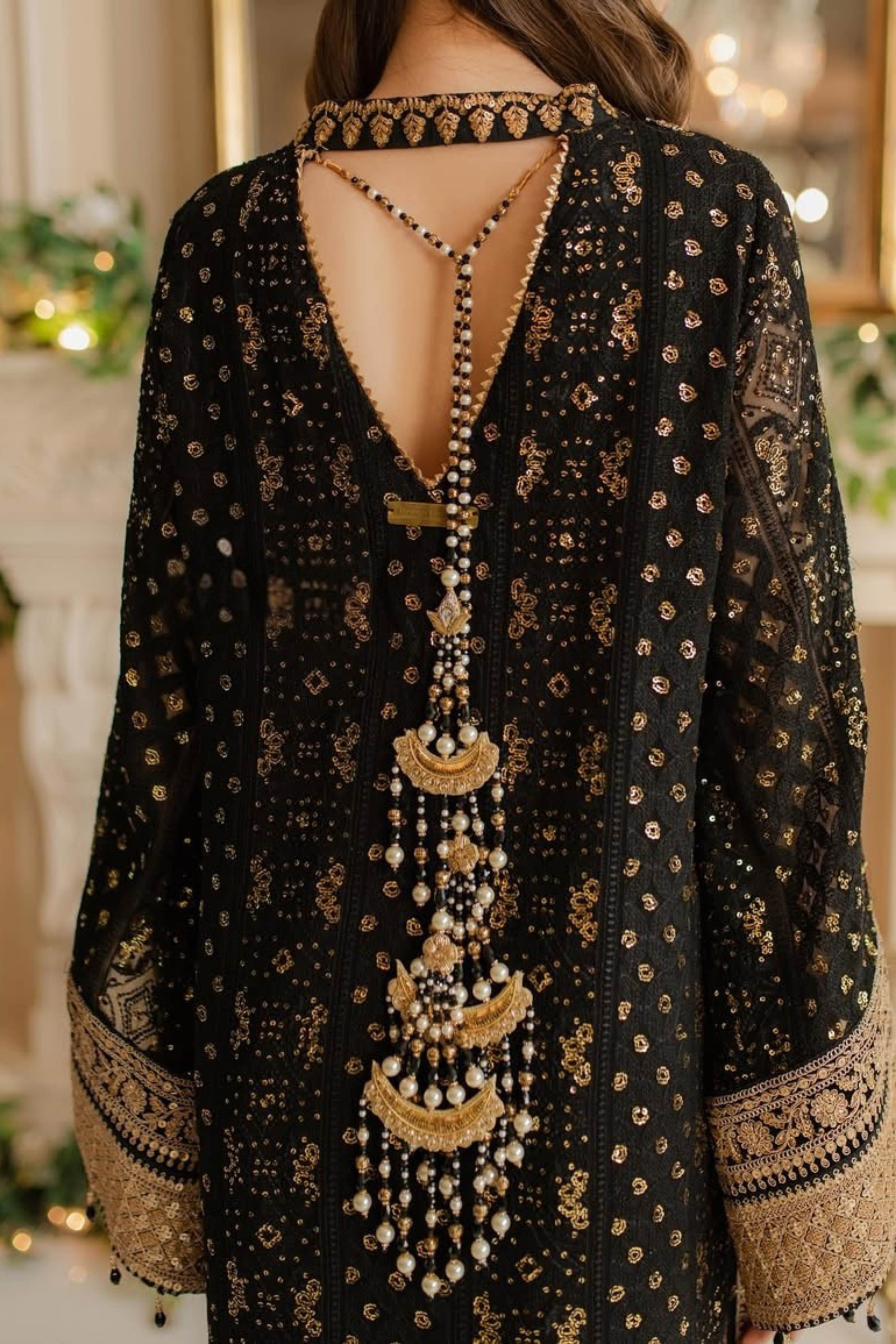 Black embroidered dress with gold detailing and a long necklace.