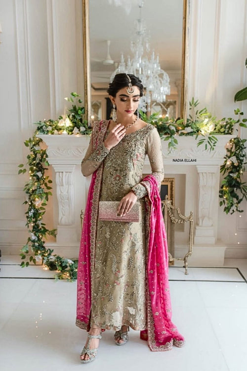 Woman in traditional outfit with pink dupatta in a decorated room