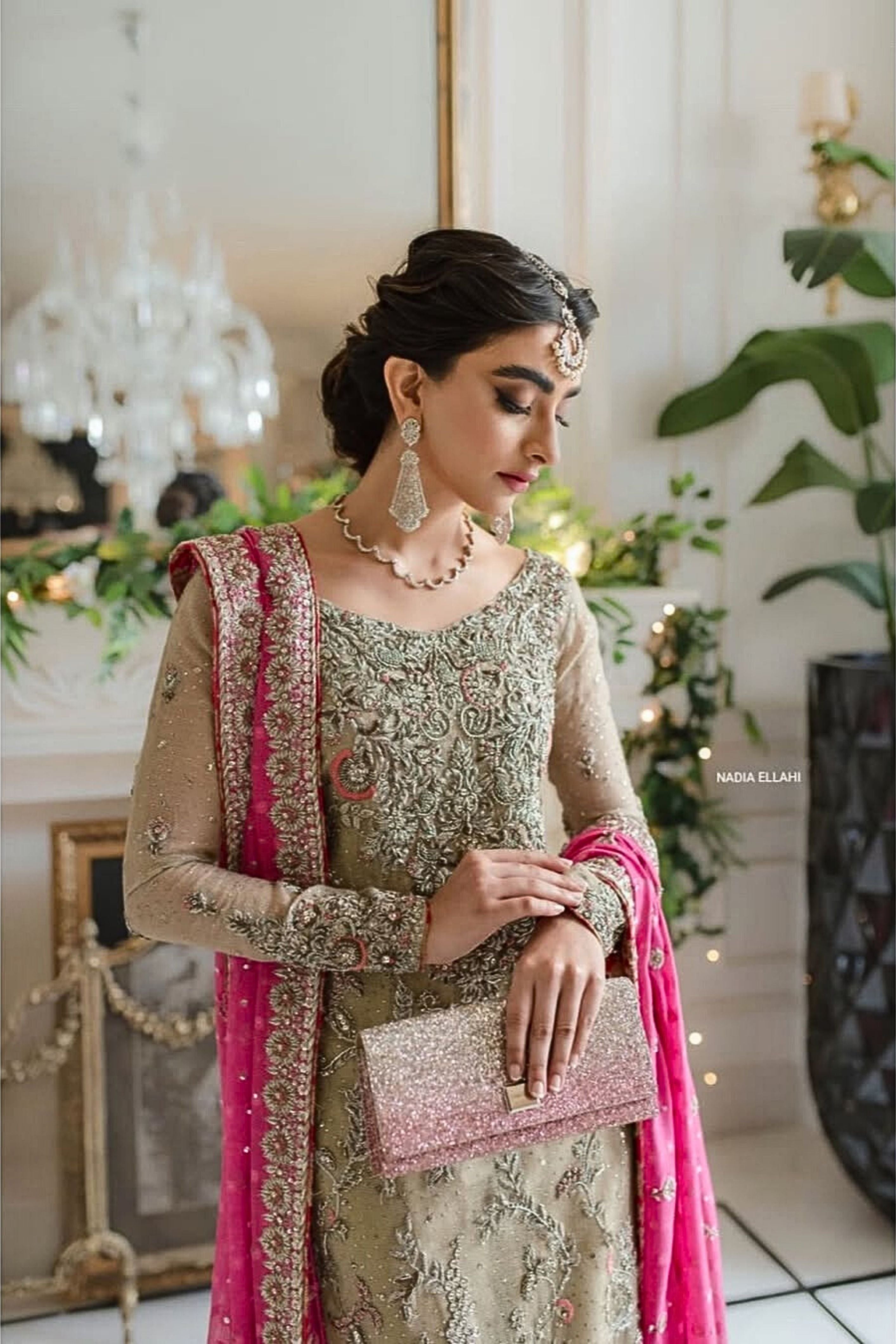 Woman in traditional attire with pink and gold details in a decorated indoor setting