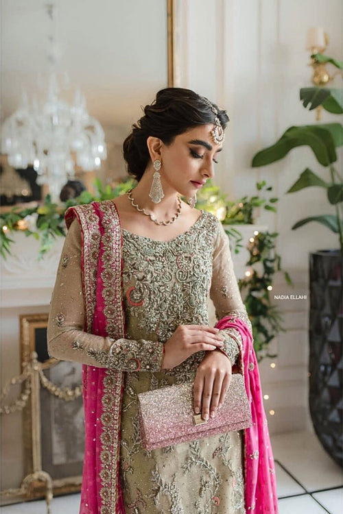 Woman in traditional attire with pink and gold details in a decorated indoor setting