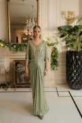 Woman in a green dress standing in an elegant room with decorative elements.