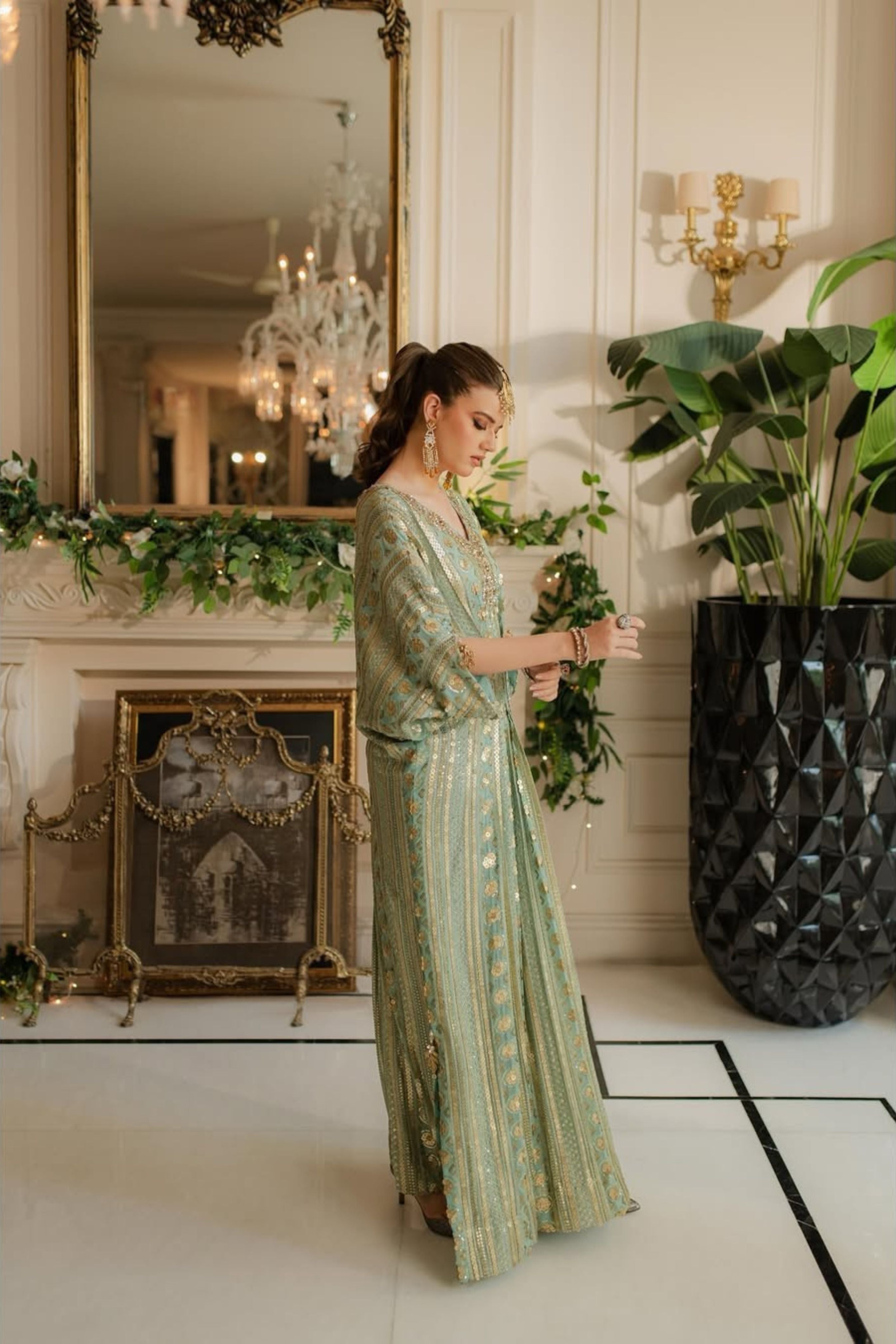 Woman in a green dress standing in an elegant room with decorative elements.