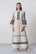 an russian model wearing An ivory floor-length Chanderi dress featuring dramatic bell sleeves and vertical panels of tonal geometric hand-cut appliqué.