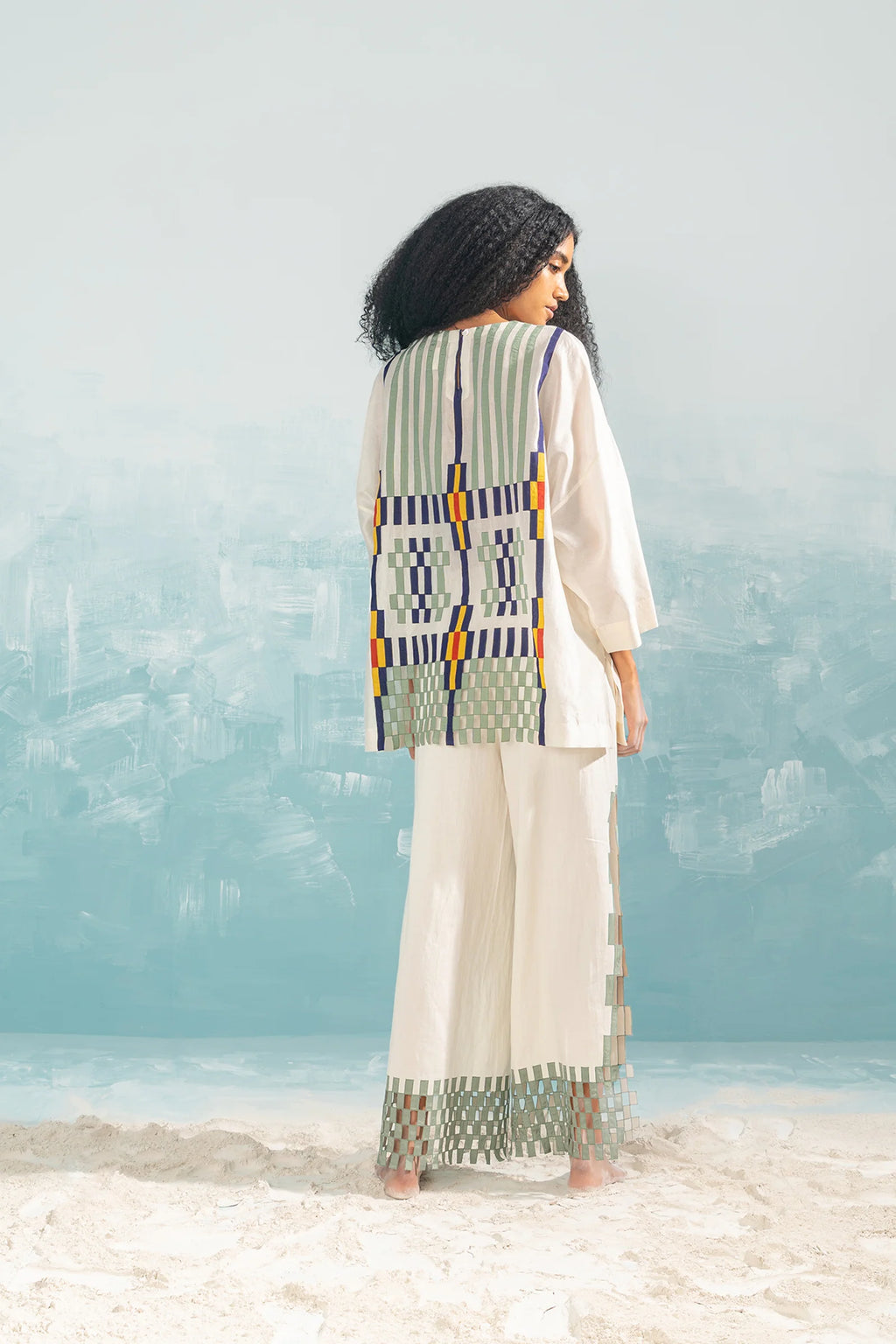 An ivory Cotton Silk Chanderi shirt featuring vertical panels of geometric cutwork and tonal hand-cut appliqué, paired with matching wide-leg trousers.