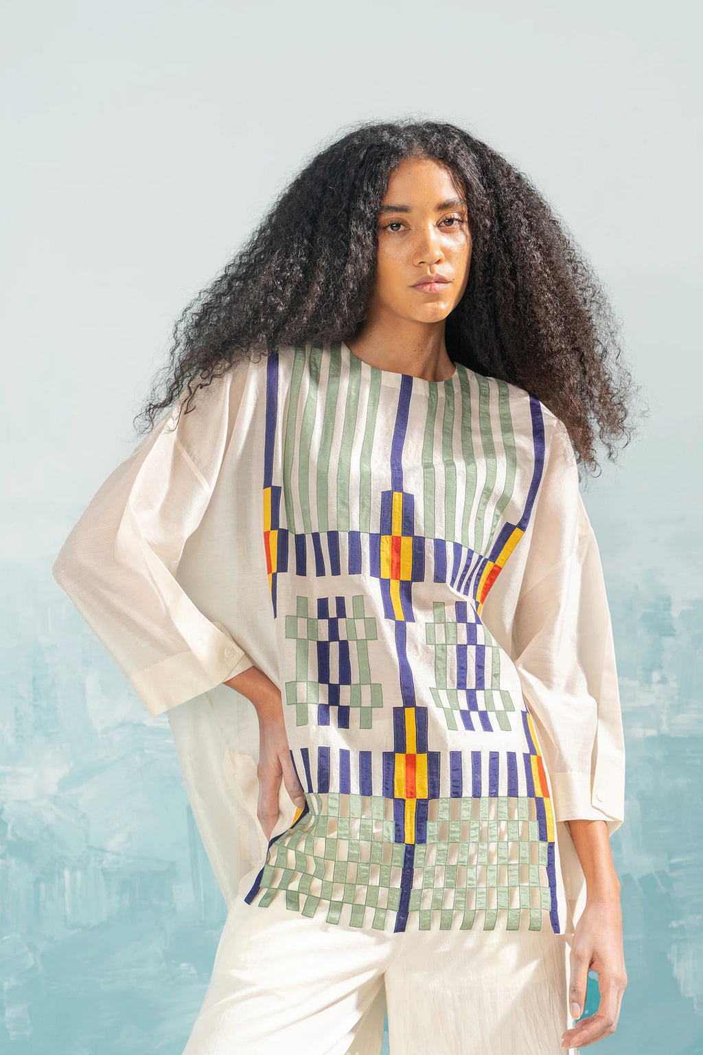 An ivory Cotton Silk Chanderi shirt featuring vertical panels of geometric cutwork and tonal hand-cut appliqué, paired with matching wide-leg trousers.