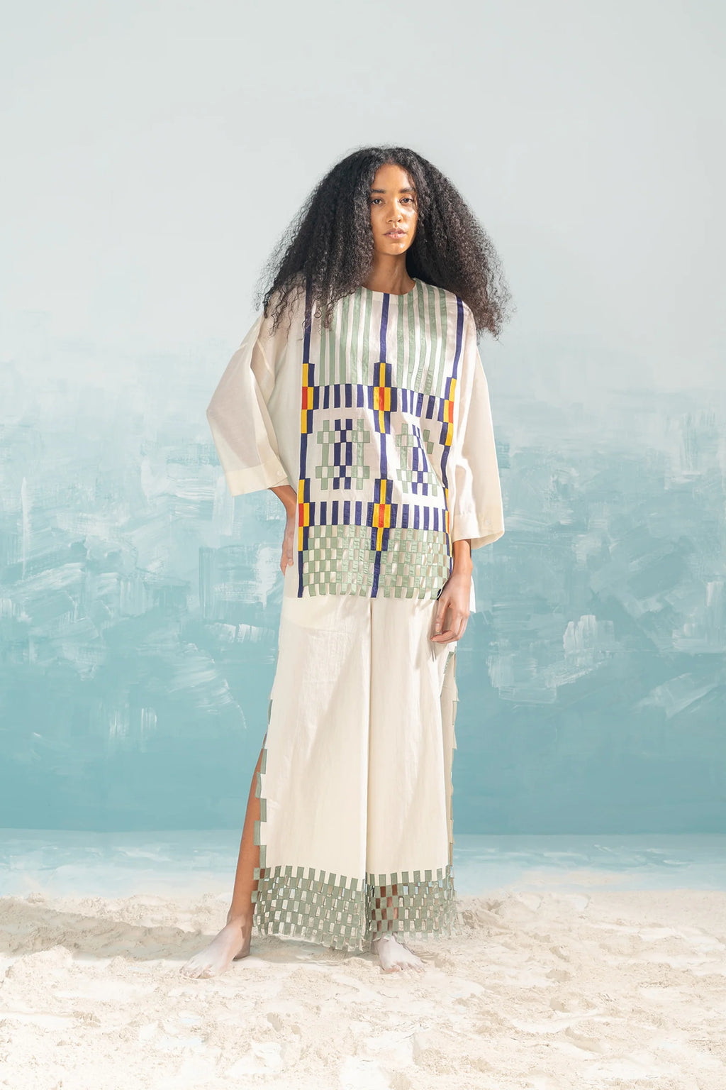 An ivory Cotton Silk Chanderi shirt featuring vertical panels of geometric cutwork and tonal hand-cut appliqué, paired with matching wide-leg trousers.
