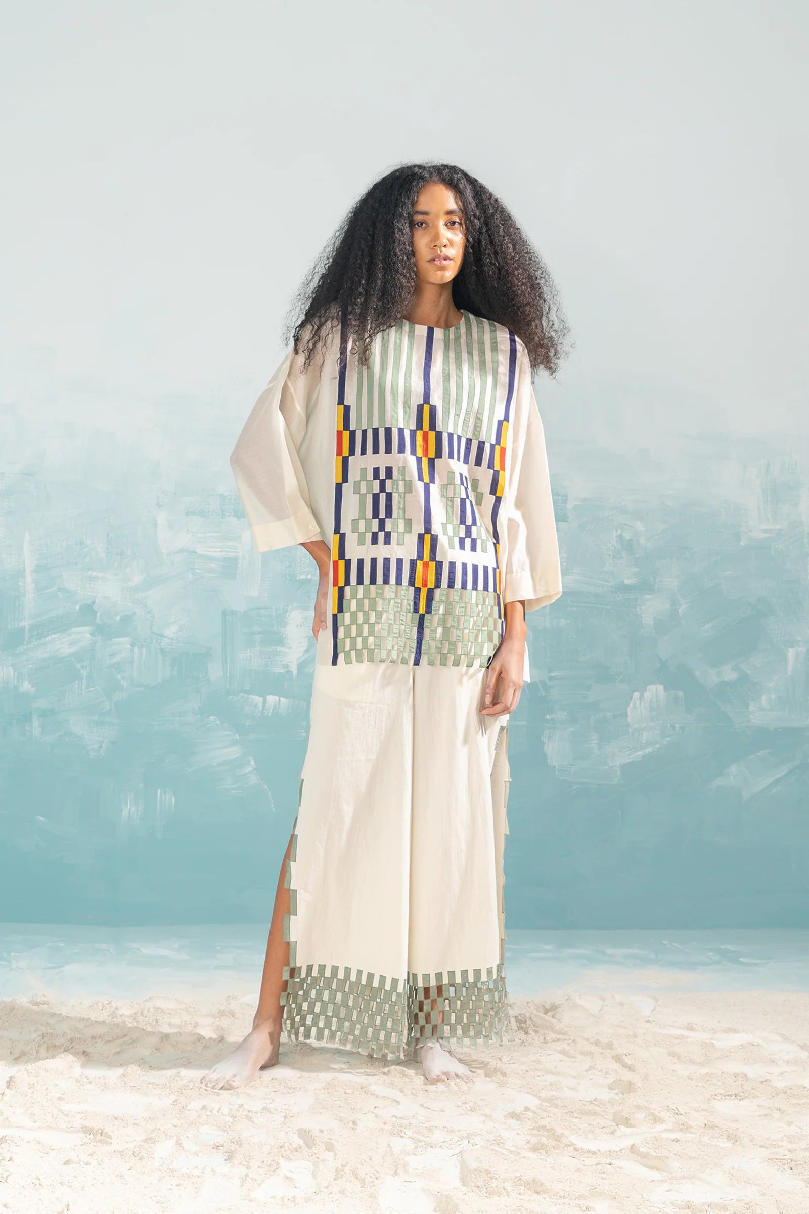 An ivory Cotton Silk Chanderi shirt featuring vertical panels of geometric cutwork and tonal hand-cut appliqué, paired with matching wide-leg trousers.