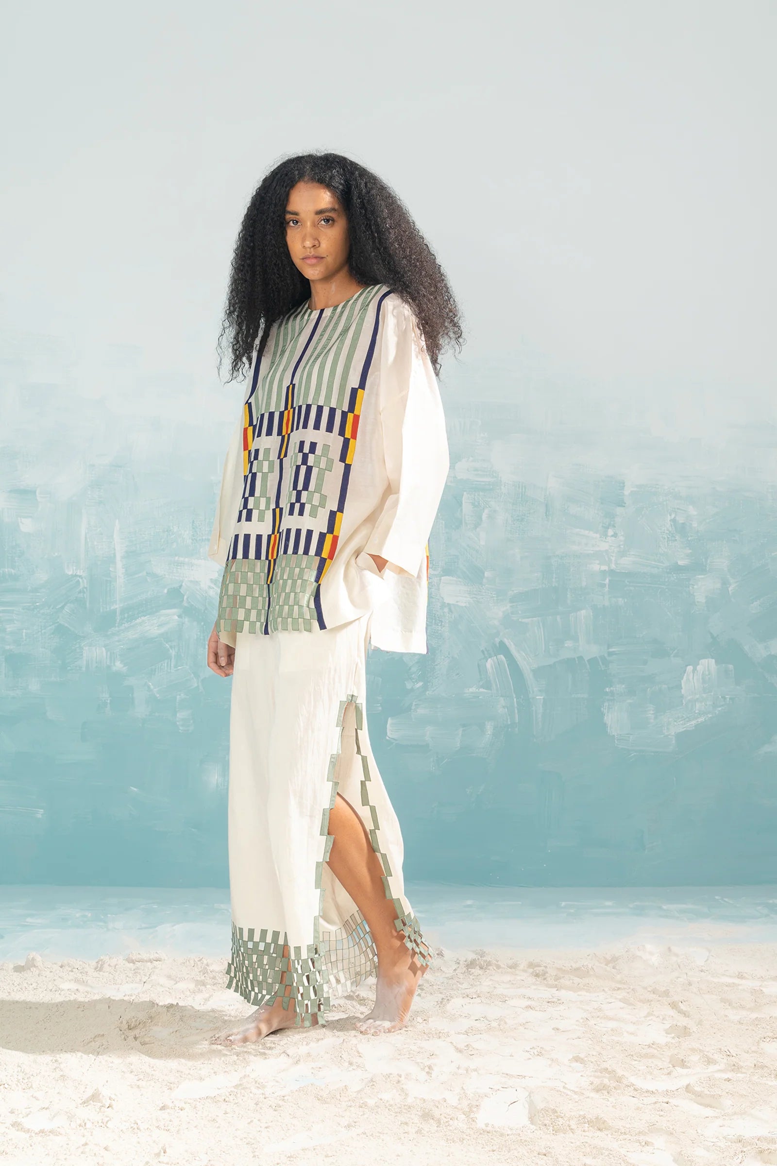 An ivory Cotton Silk Chanderi shirt featuring vertical panels of geometric cutwork and tonal hand-cut appliqué, paired with matching wide-leg trousers.
