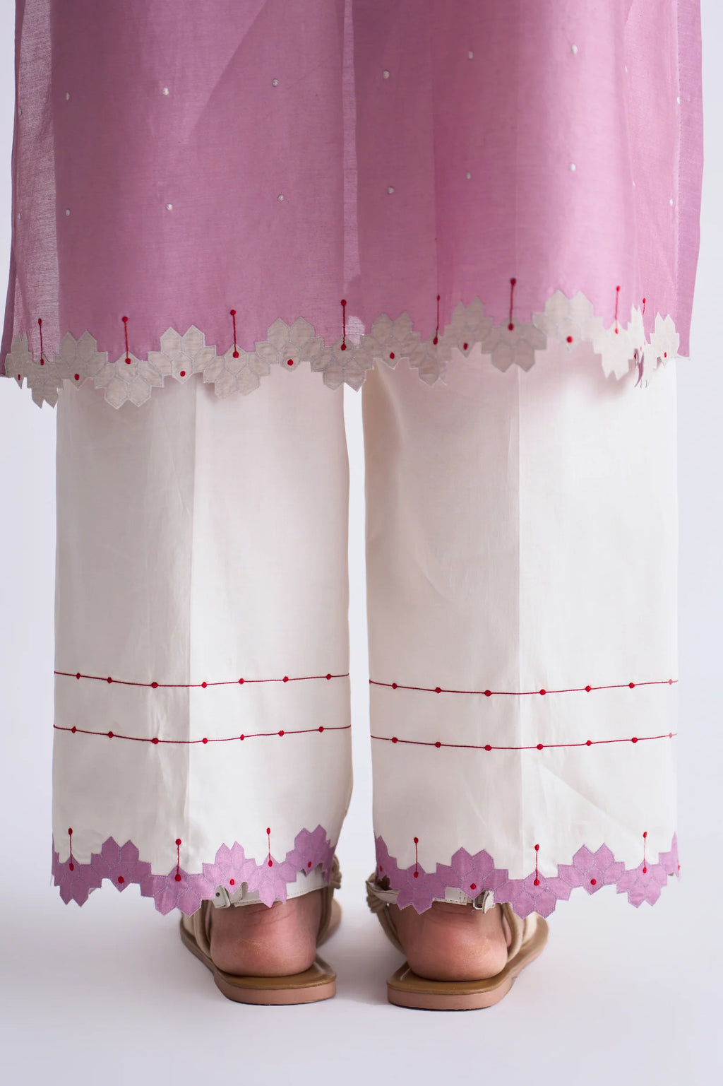 A model in a blush pink A-line Chanderi shirt with ivory geometric hand-cut appliqué along the hem and sleeves, paired with matching ivory pants.