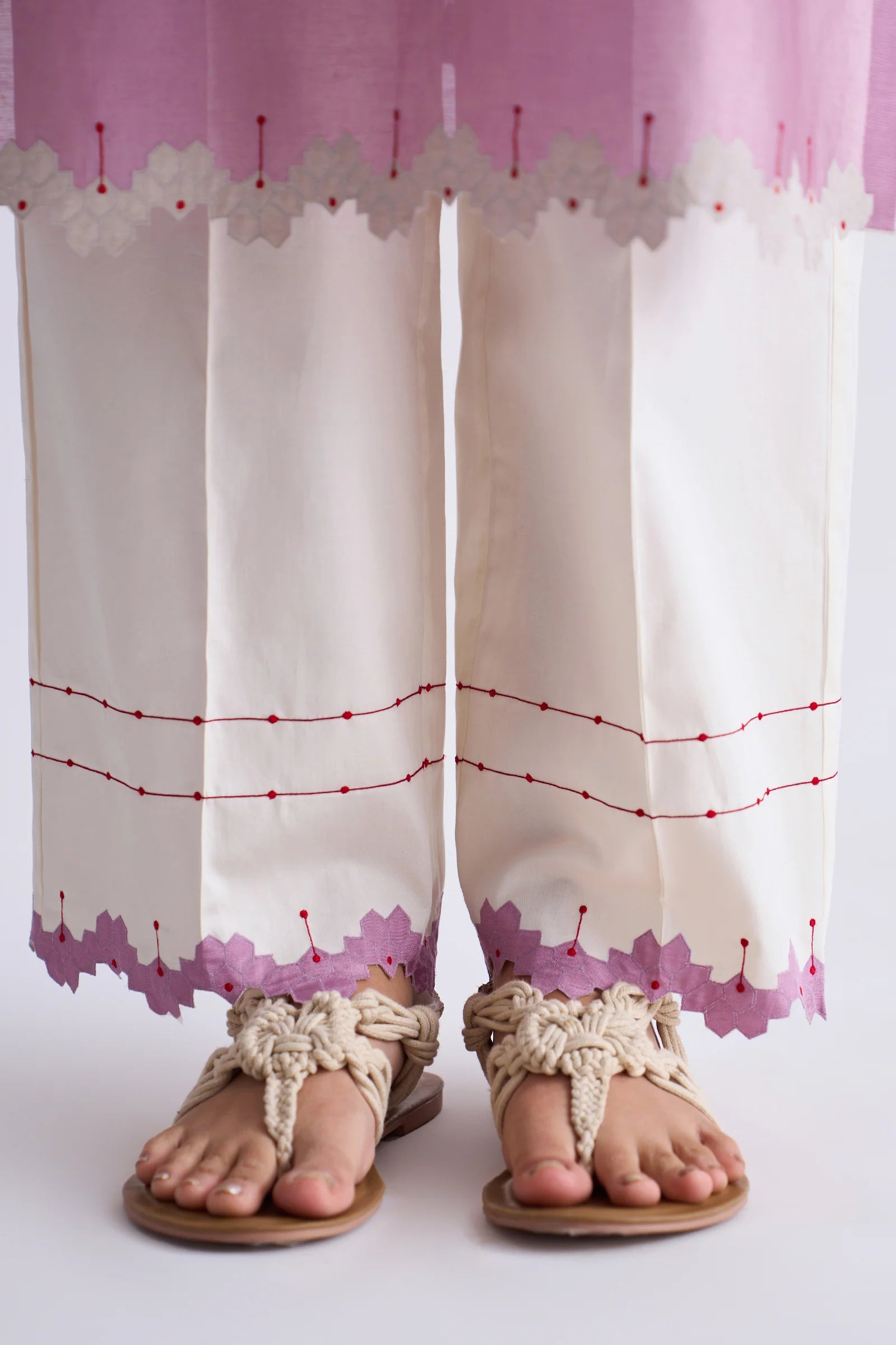 A model in a blush pink A-line Chanderi shirt with ivory geometric hand-cut appliqué along the hem and sleeves, paired with matching ivory pants.