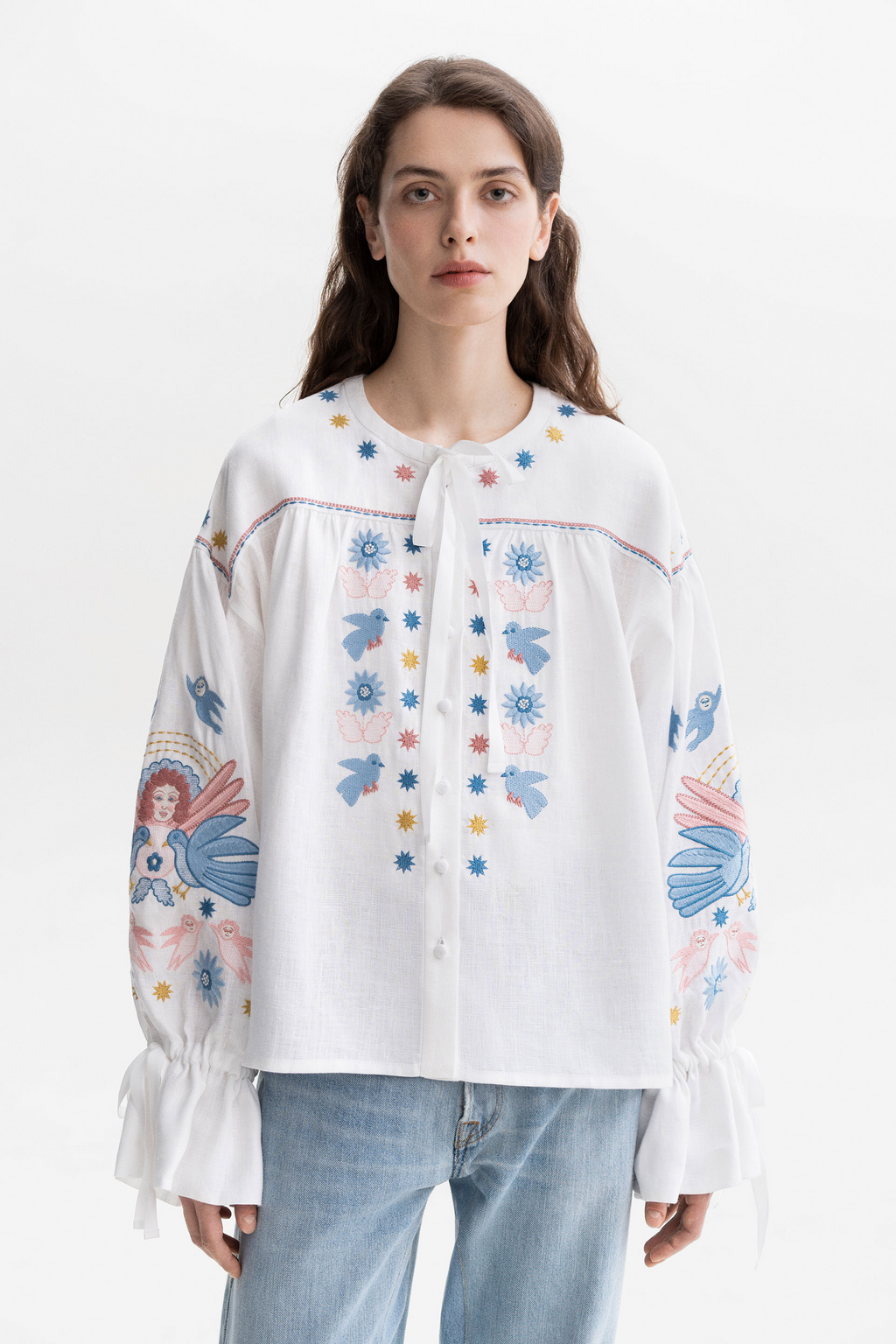 Woman wearing a white embroidered blouse with floral patterns on a white background