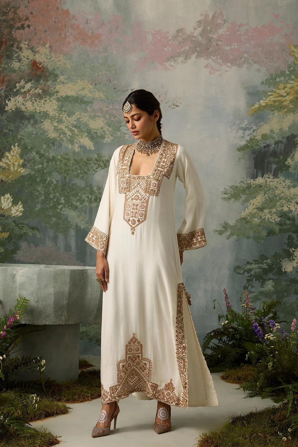 Woman in a white embroidered dress standing in a garden setting