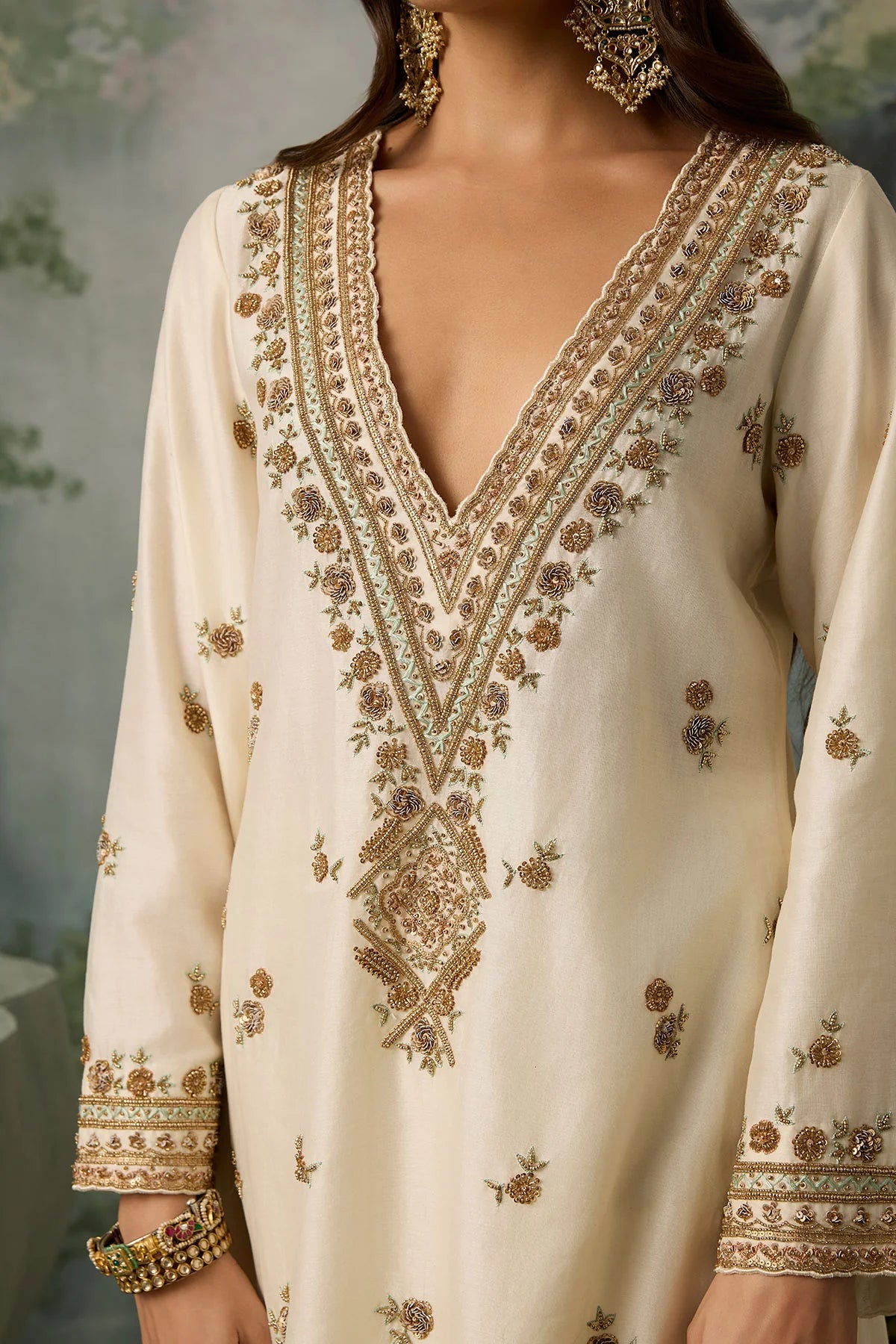 Beige embroidered dress with gold details on a blurred background