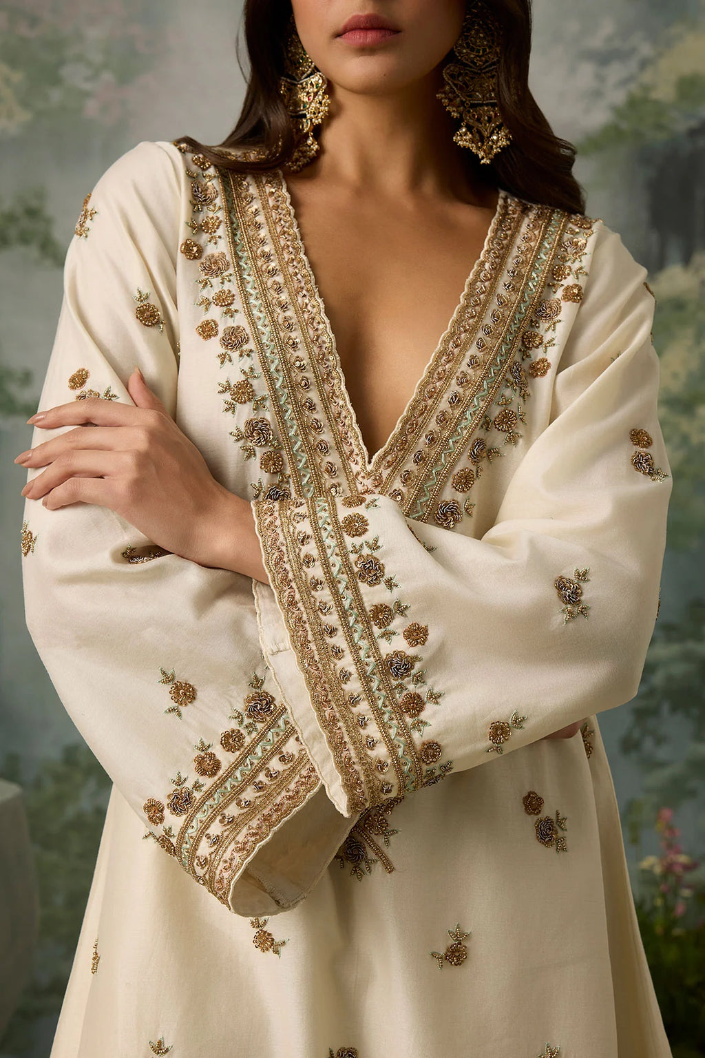 Woman wearing a cream-colored embroidered dress with a blurred natural background