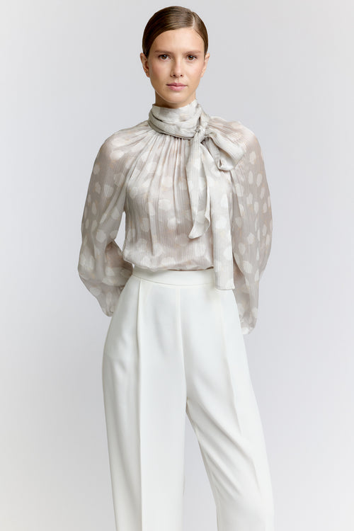 Woman wearing a sheer polka dot blouse with a white background