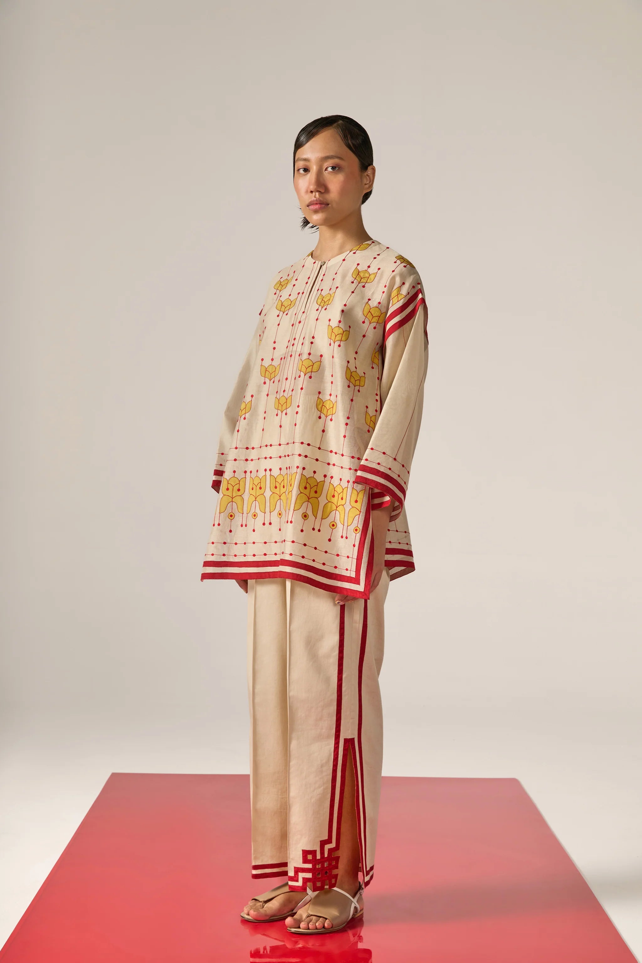 An asian model wearing white Cotton Silk Chanderi shirt featuring a drop-shoulder silhouette with detailed geometric cutwork panels and tonal threadwork along the sleeves and back.