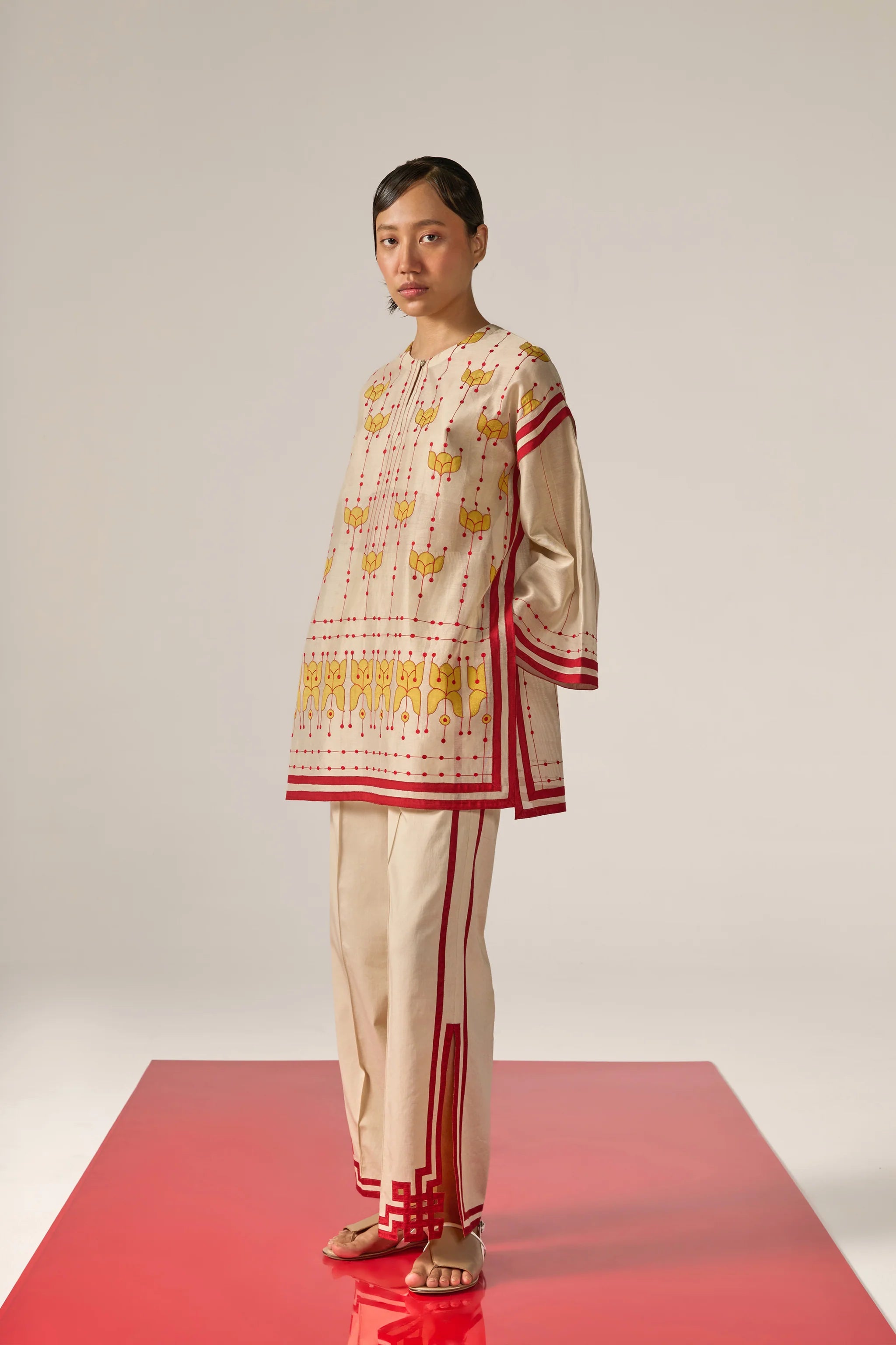 An asian model wearing white Cotton Silk Chanderi shirt featuring a drop-shoulder silhouette with detailed geometric cutwork panels and tonal threadwork along the sleeves and back.