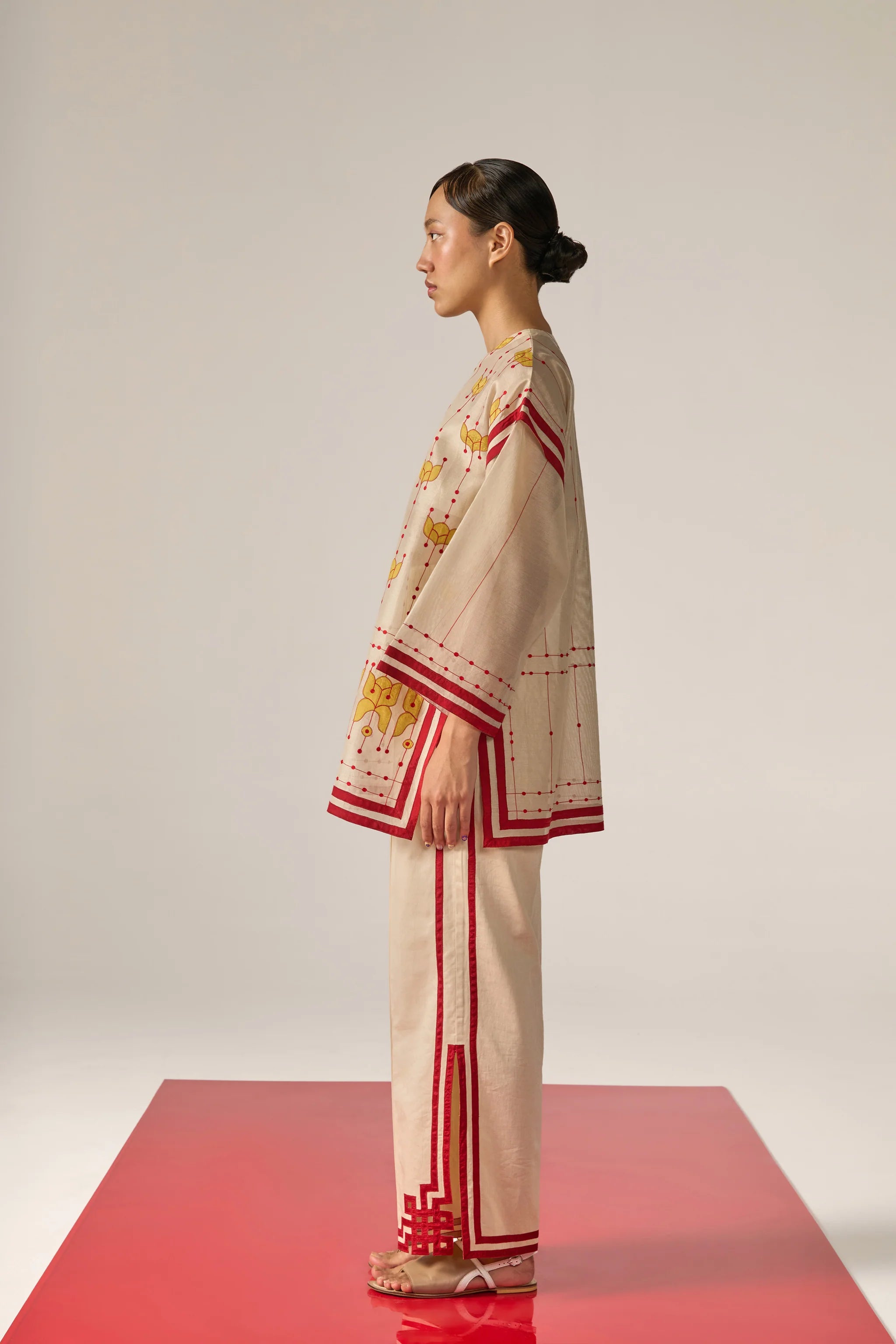 An asian model wearing white Cotton Silk Chanderi shirt featuring a drop-shoulder silhouette with detailed geometric cutwork panels and tonal threadwork along the sleeves and back.