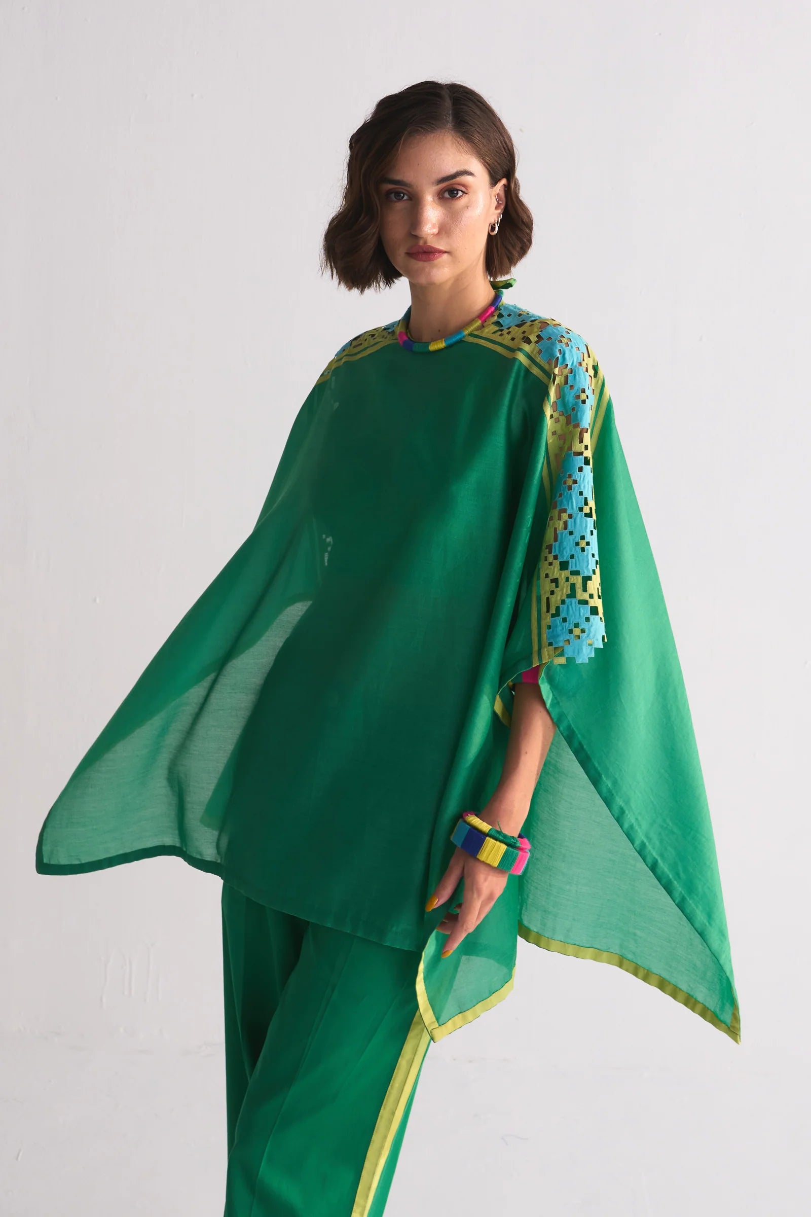 A vibrant green Chanderi shirt featuring blue and lime green geometric hand-cut appliqué and cutwork on the shoulders, paired with matching wide-leg trousers.