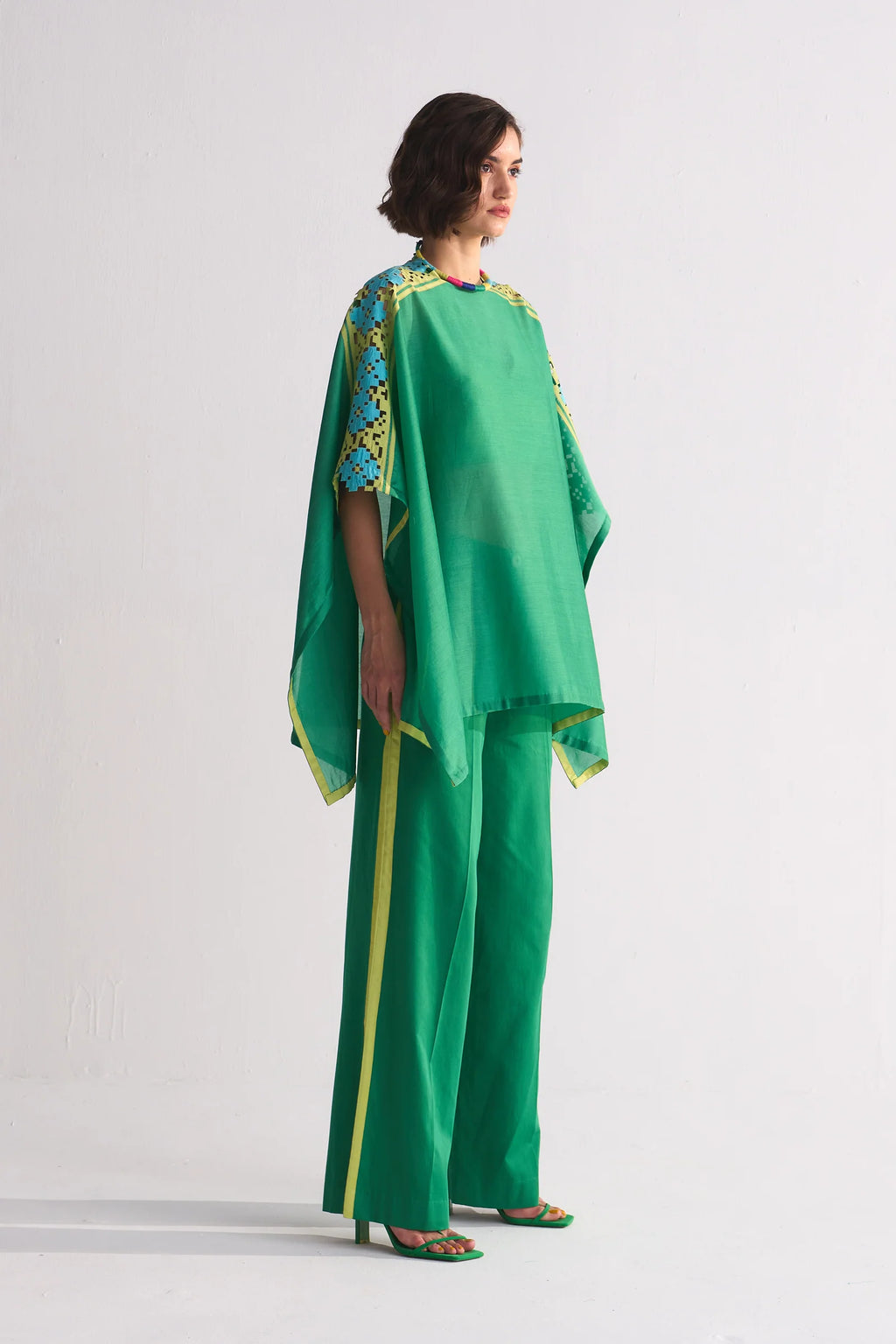 A vibrant green Chanderi shirt featuring blue and lime green geometric hand-cut appliqué and cutwork on the shoulders, paired with matching wide-leg trousers.