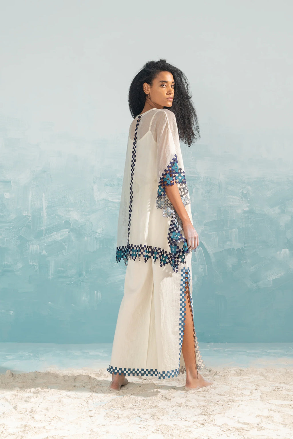 A model in an ivory Chanderi shirt with vertical geometric cutwork panels and tonal hand-cut appliqué, featuring a relaxed free-size fit.
