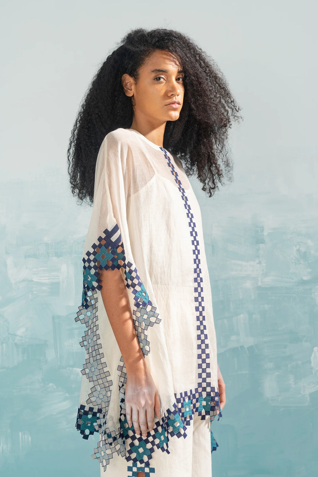 A model in an ivory Chanderi shirt with vertical geometric cutwork panels and tonal hand-cut appliqué, featuring a relaxed free-size fit.