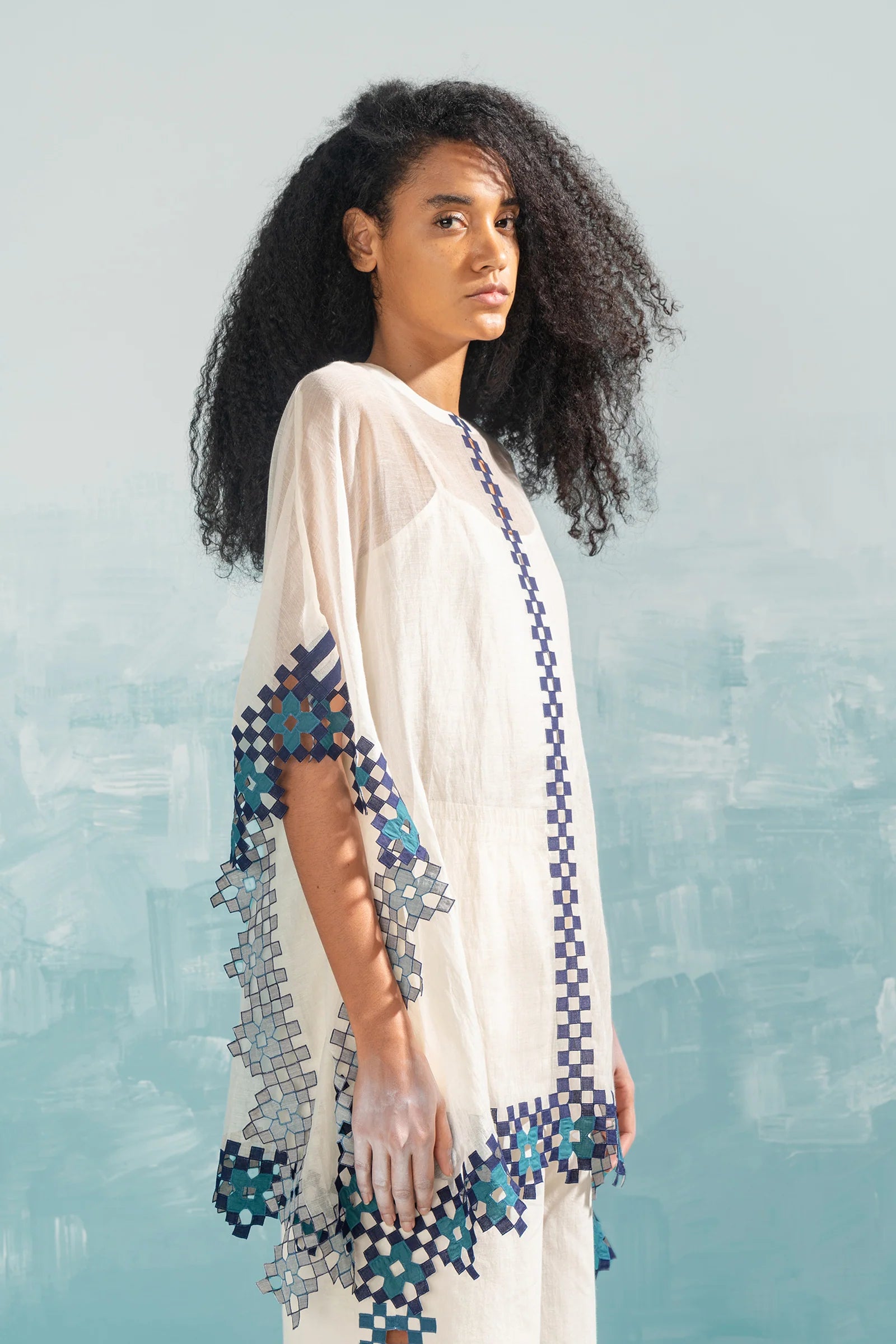 A model in an ivory Chanderi shirt with vertical geometric cutwork panels and tonal hand-cut appliqué, featuring a relaxed free-size fit.