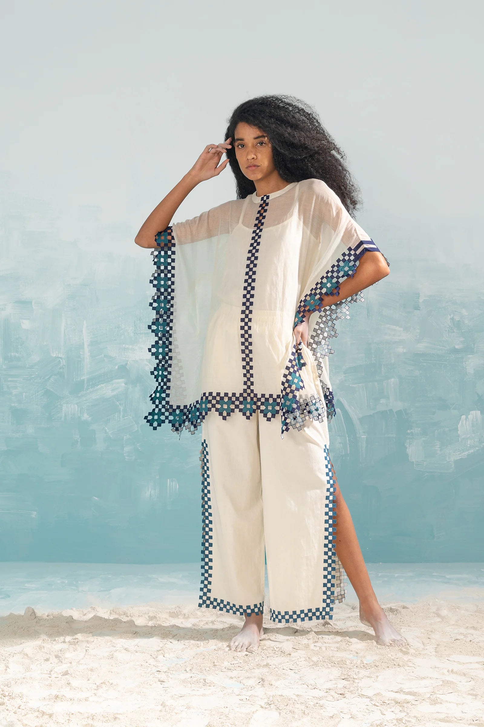 A model in an ivory Chanderi shirt with vertical geometric cutwork panels and tonal hand-cut appliqué, featuring a relaxed free-size fit.