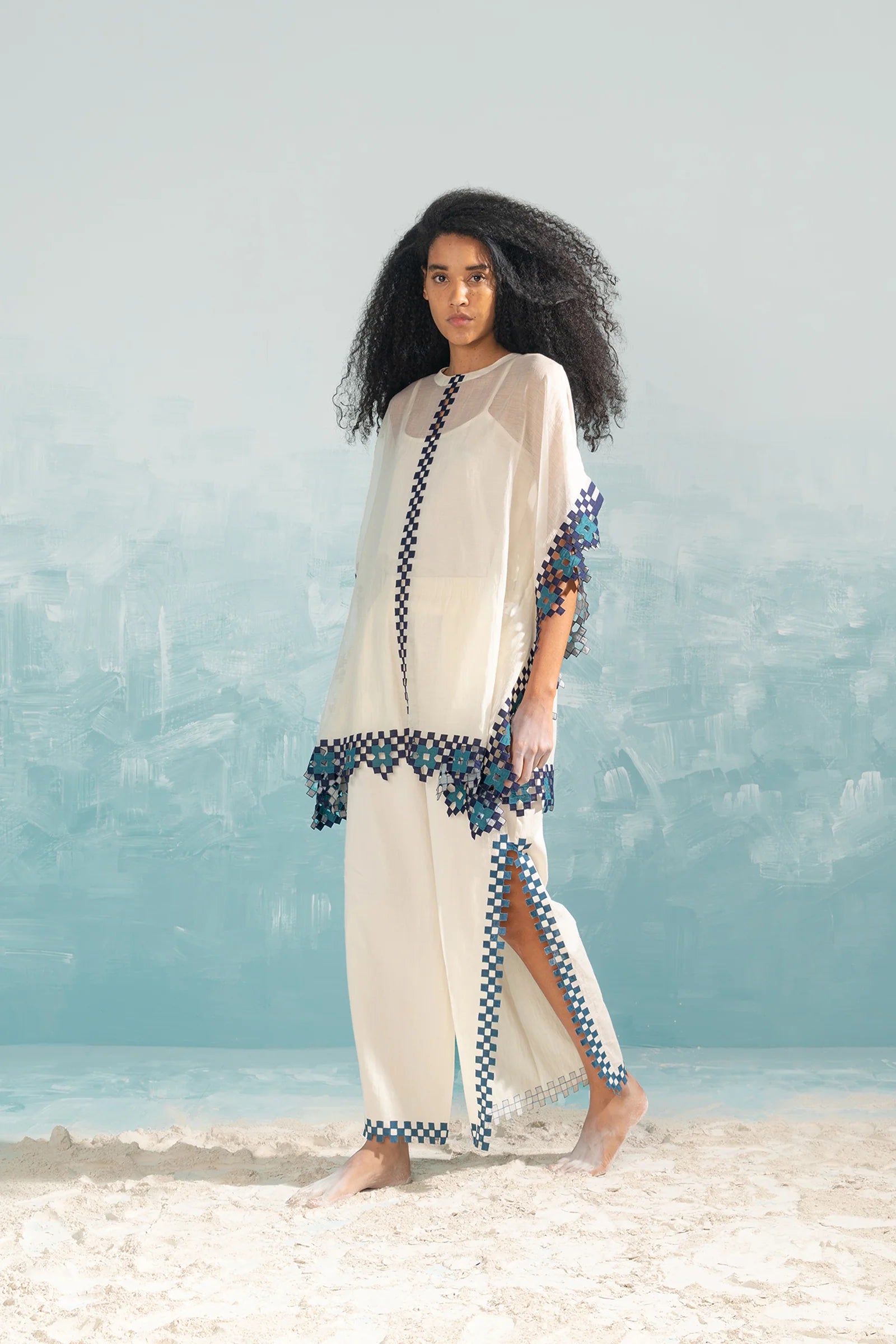 A model in an ivory Chanderi shirt with vertical geometric cutwork panels and tonal hand-cut appliqué, featuring a relaxed free-size fit.
