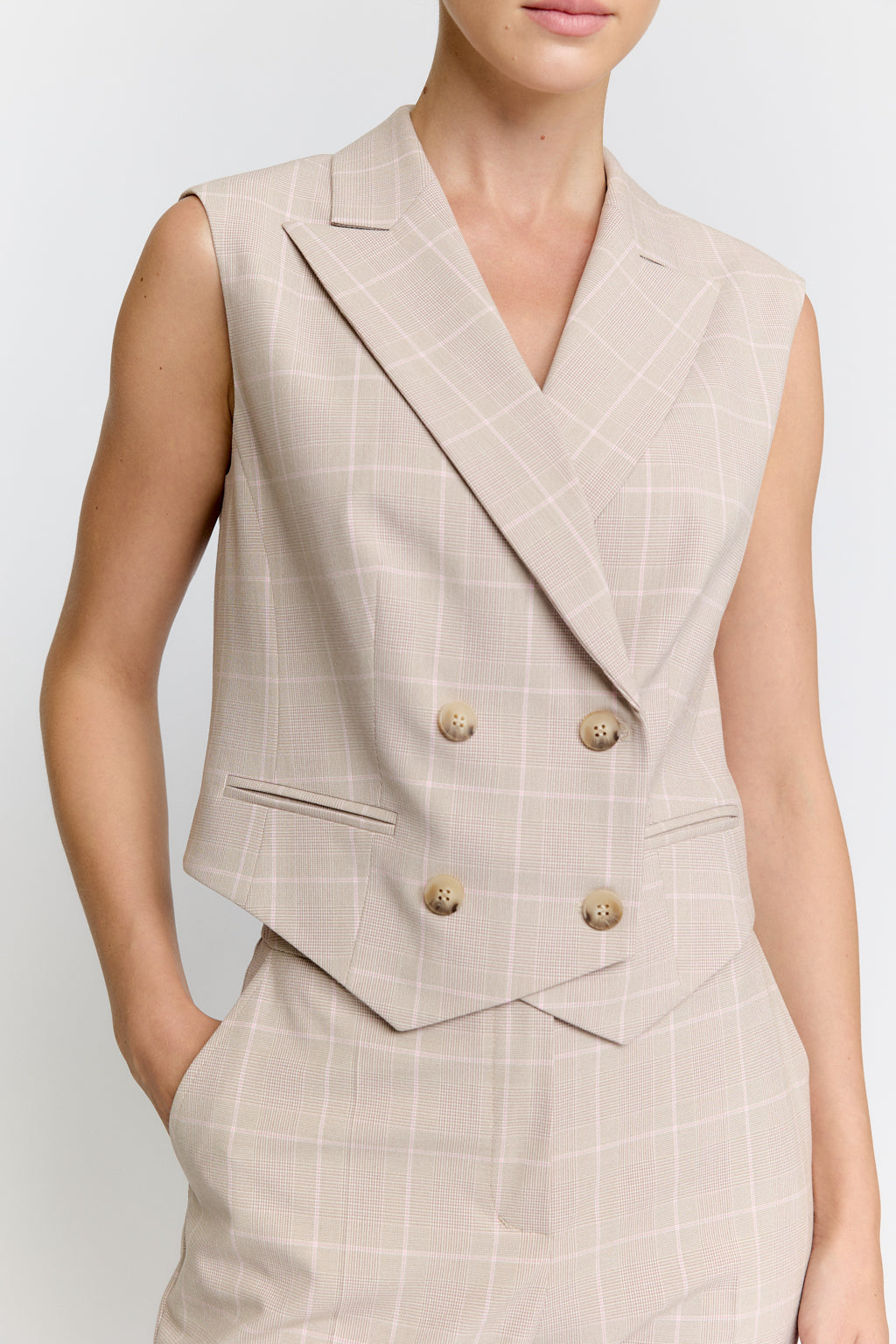 Beige plaid vest with gold buttons on a plain background