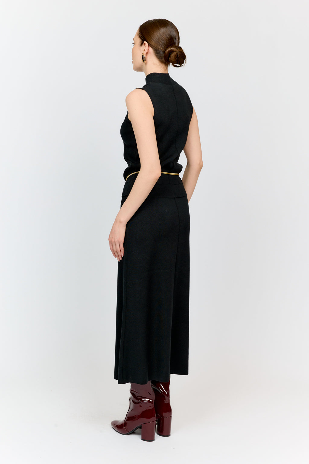 Woman wearing a black sleeveless dress with a high neckline on a white background