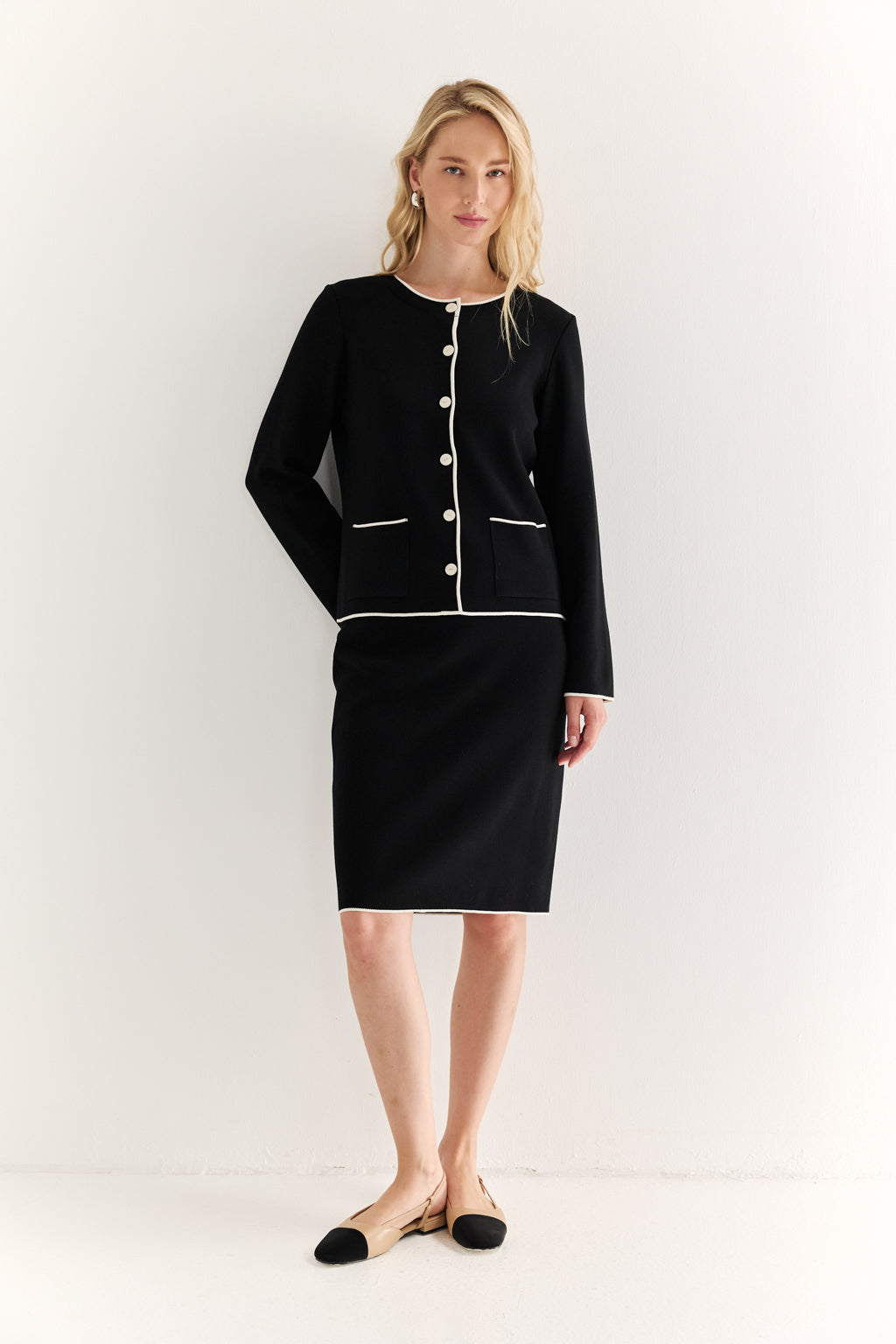 Woman wearing a black suit with white buttons on a white background