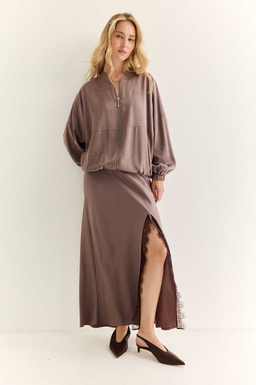 Woman wearing a brown outfit with a long skirt on a white background