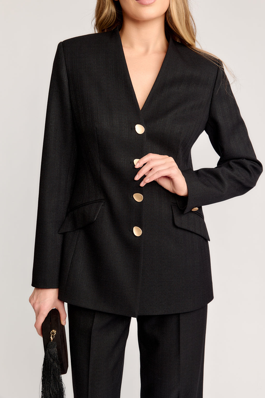 Black suit with gold buttons worn by a person on a light gray background