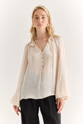 Woman wearing a beige blouse with a plain background