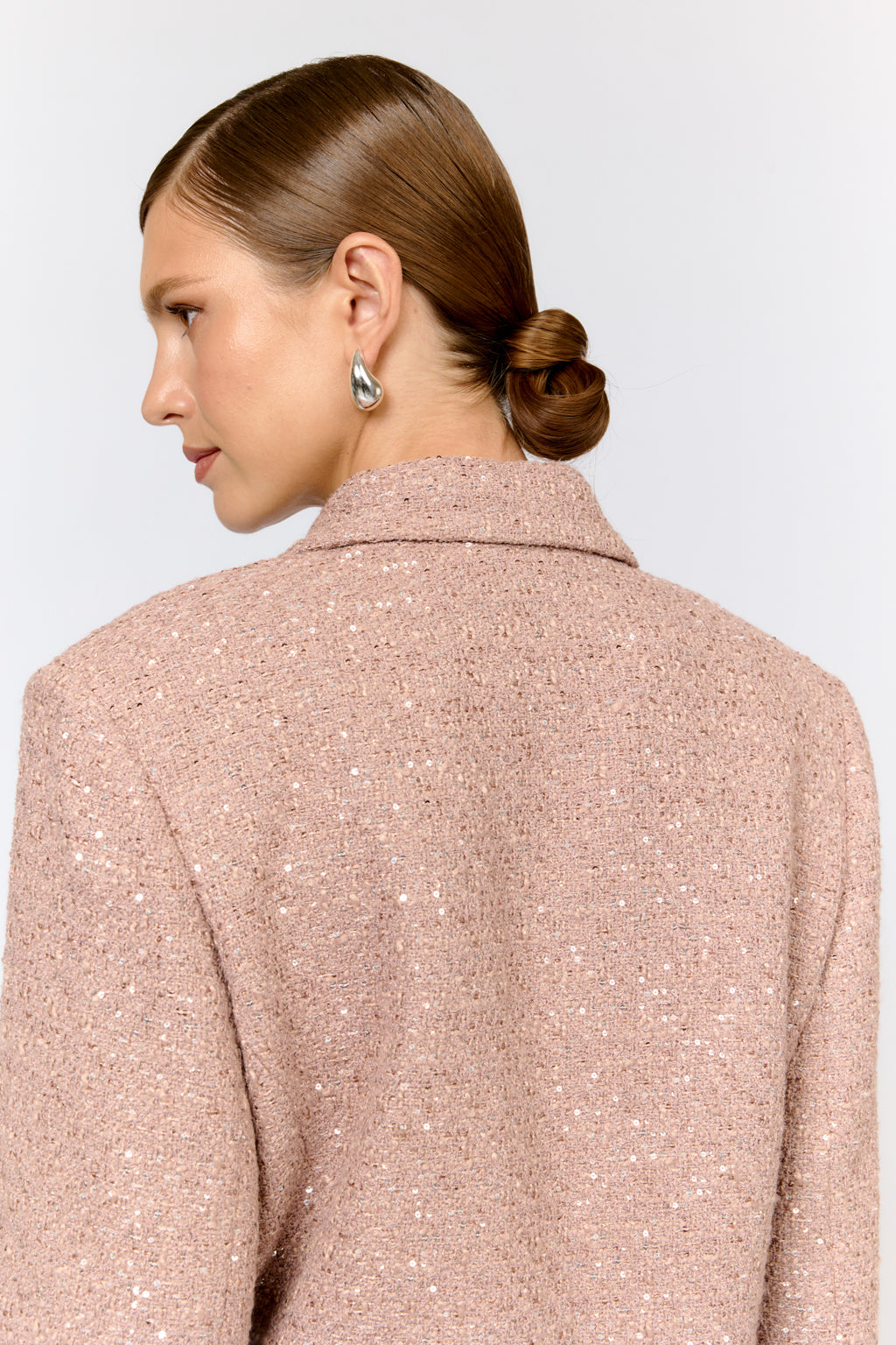 Person wearing a light pink textured coat on a plain background
