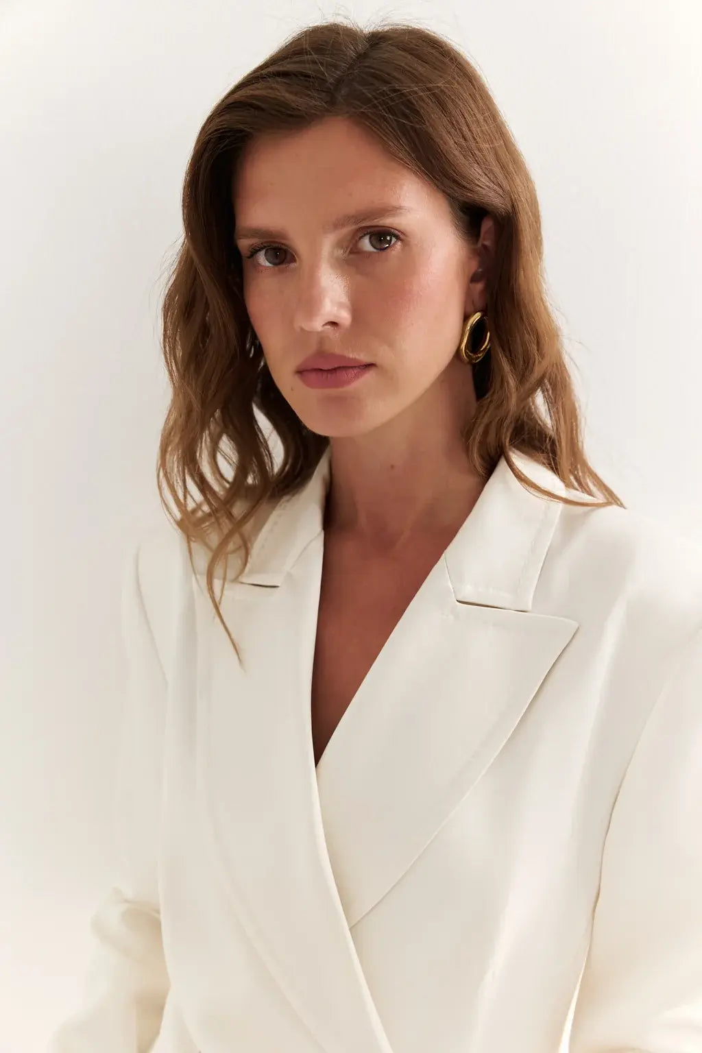 AYRA Store beautiful woman standing wearing  milk-colored double-breasted sculptural luxury jacket dress with architectural shoulders and hourglass silhouette